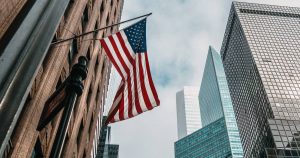 the-usa-or-united-states-of-america-flag-on-a-flagpole-near-skyscrapers-under-a-cloudy-sky(1)